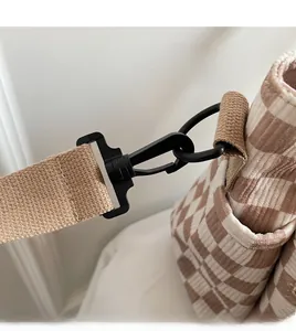 Close-up of durable black swivel hook and light brown woven strap on corduroy tote bag