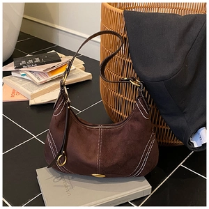 Detail of dark brown suede shoulder bag with contrast white stitching and gold hardware
