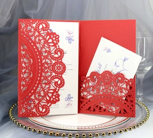 Detailed laser-cut red wedding invitation with floral insert on a silver decorative tray