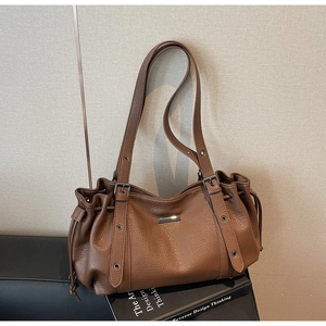 Détail d'un sac cabas en cuir marron à motif litchi avec boucles en métal argenté