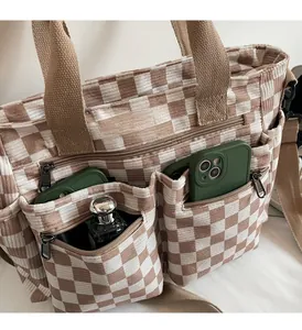 Detailed view of checkered corduroy tote bag showing functional external zipper pockets