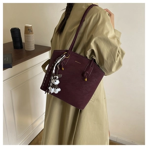 Detail of burgundy bucket bag featuring gold hardware, silk scarf, and dog charm detail