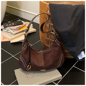 Detail of dark brown suede crescent hobo bag with white contrast stitching and gold zipper