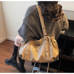 Beige oversized tote bag with lychee texture and drawstring detail shown on model's shoulder