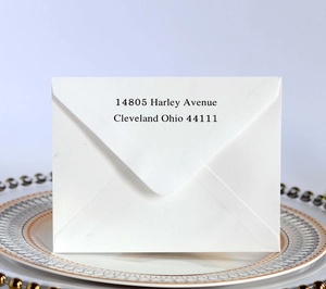 Detail of white invitation envelope with elegant black serif printing on a ceramic plate