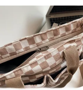 Detailed macro view of the YKK metal zipper and plaid corduroy fabric on a tote bag