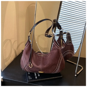 Detailed macro of dark brown suede hobo bag featuring contrasting white stitching and zipper