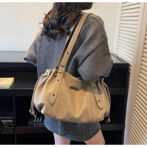 Détail du sac cabas beige avec cordon de serrage et bandoulière sur un modèle