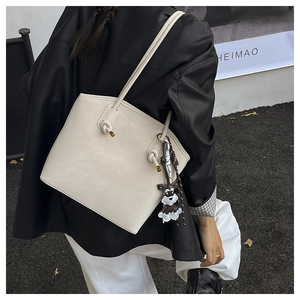 Detail of off-white leather tote bag with knotted strap and golden metal accents