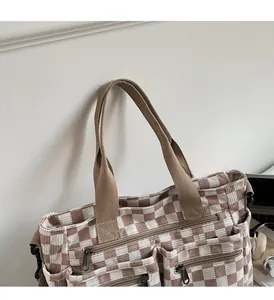 Detail of checkered canvas tote bag with multi-zipper pockets and wide straps