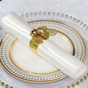 Detailed laser-cut gold carriage napkin ring on a white satin napkin for luxury weddings