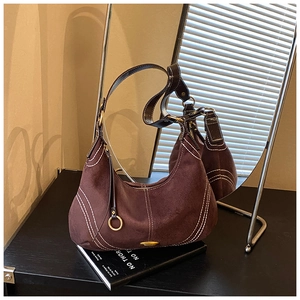 Detail of dark brown suede hobo bag featuring white contrast stitching and gold hardware