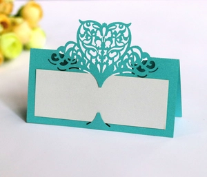 Detail of laser-cut heart pattern on a mint green wedding place card with paper texture