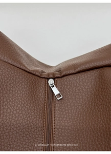 Macro view of brown lychee grain leather tote bag with silver zipper and fine stitching