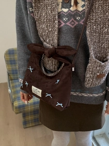 Brown faux suede hobo bag featuring light blue decorative bows and a long shoulder strap