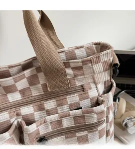 Detail of checkered corduroy tote bag featuring multiple zipper pockets and adjustable strap