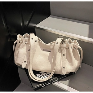 Détail du sac cabas en cuir crème avec cordon de serrage et bandoulière à œillets