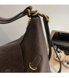 Detailed close-up of dark brown lychee texture leather bag with gold ring hardware