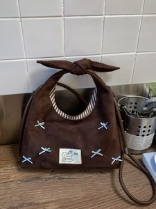 Retro brown suede dumpling bag with a blue bow and pearl decor on wooden surface