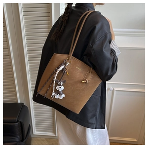 Detail of dark brown tote bag with woven tassels and cute animal charm on shoulder strap