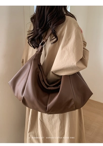 Detail of dark brown leather tote featuring retro pleated texture and silver metal rings
