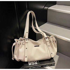 Détail du sac cabas en cuir crème avec boucles argentées sur décor urbain moderne