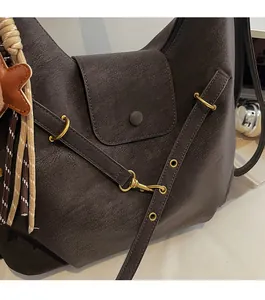 Close-up of matte dark brown suede tote with gold hardware and stylish tassel detail