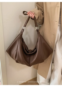 Detail of dark brown leather tote bag showing pleated texture and silver metal rings