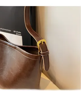 Detail of vintage brown leather shoulder bag with polished gold buckle and fine stitching