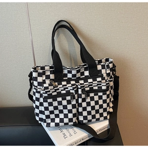 Detailed view of checkerboard corduroy tote with dual zipper pockets and adjustable strap