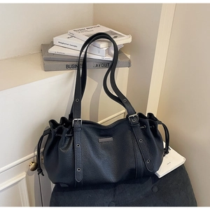 Détail du cabas en cuir grainé noir avec cordon de serrage et plaque métallique argentée