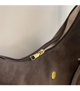 Close-up of golden hardware zipper and herringbone fabric lining on brown leather tote bag