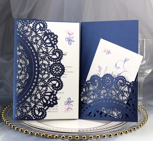Detail of laser-cut navy blue wedding invitation set with floral inner card on glass tray