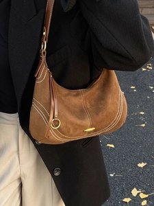 Caramel suede hobo bag with contrast stitching and leather tassel on a model shoulder