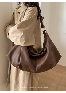 Detail of soft brown pebble leather hobo bag with wide strap and retro pleated design