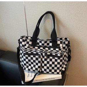 Close-up of black and white checkered canvas tote bag with functional zippers and strap
