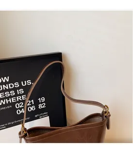 Detail of dark brown leather handbag featuring gold metal buckle and reinforced strap