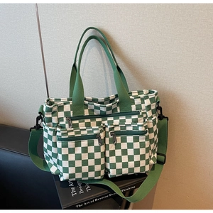 Detail of green checkerboard canvas tote with multi-pocket design on a book
