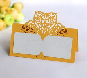 Macro shot of laser-cut heart pattern on yellow folded wedding place cards