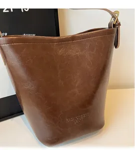 Detail view of dark brown bucket bag featuring lychee texture and embossed fashion logo