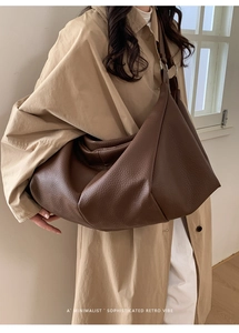 Deep brown leather tote bag worn by a model in a minimalist retro indoor setting