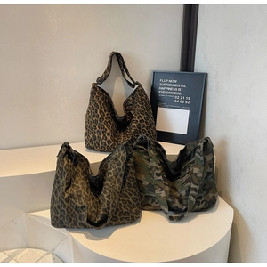 Detailed view of canvas tote bags featuring leopard and camouflage prints on a white stand