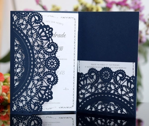 Detail of laser-cut navy blue wedding invitation with intricate lace pattern and white card