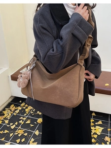 Detail of mocha brown suede tote bag featuring a creative pleated strap and bear charm