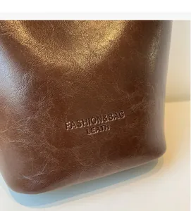 Detail of dark brown leather texture with embossed fashion logo on vintage bucket bag