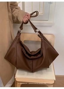 Close-up of brown pebbled leather tote bag with silver metal ring and pleated texture