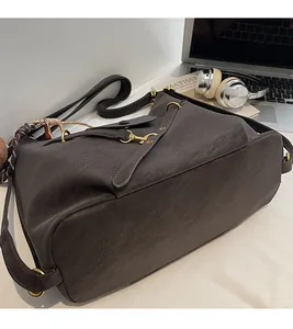 Detailed view of the dark brown leather tote bag with vintage gold metal hardware and texture