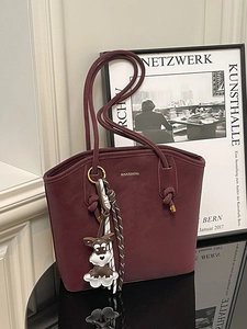 Retro burgundy bucket tote bag with gold logo and schnauzer charm on a mirror surface