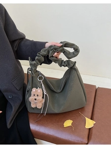 Detail of dark olive green leather tote bag with ruched strap and cute plush dog charm