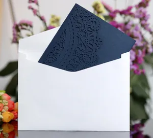 Detail of navy blue laser-cut wedding invitation with lace patterns and white envelope